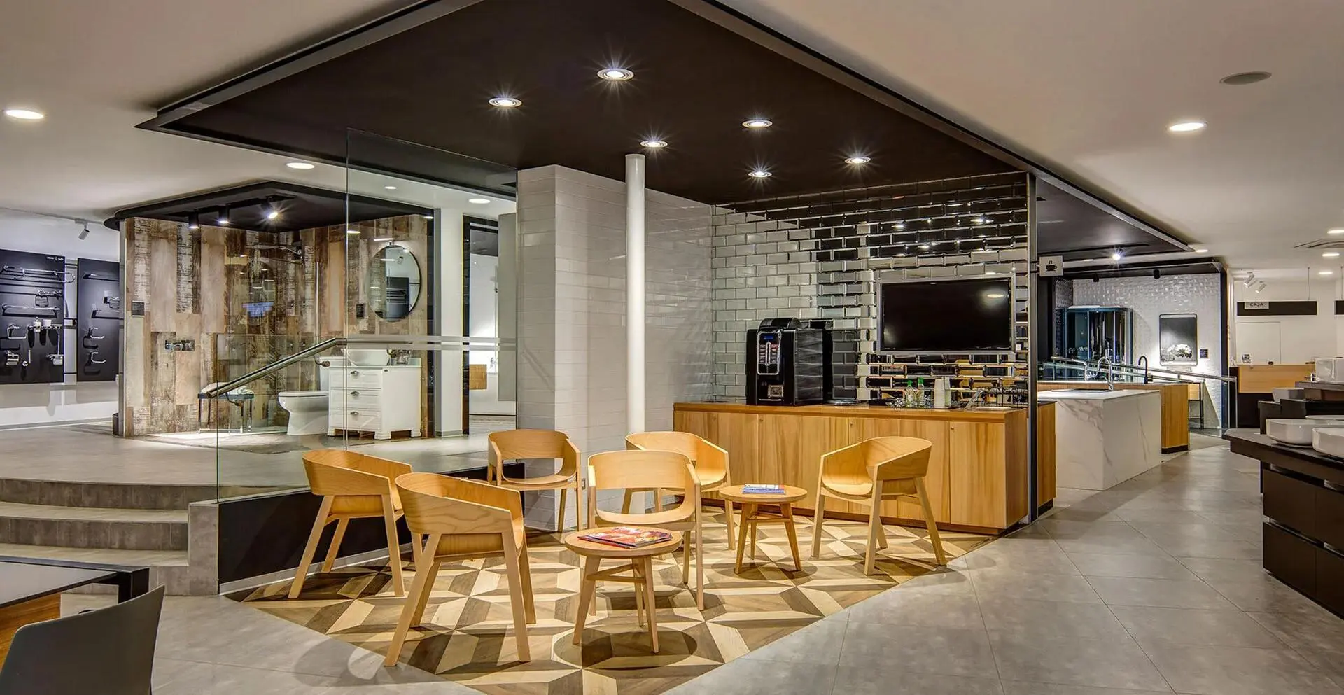 Showroom de diseño interior con exhibición de cocinas y baños con muebles de madera clara y superficies blancas