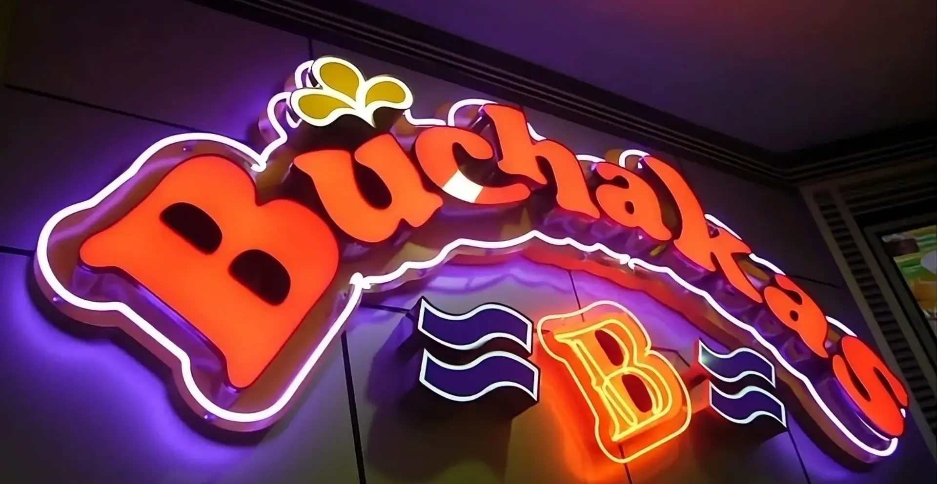 Letrero luminoso con el nombre 'Buchakas Bar' en estilo caribeño, con luz cálida y elementos festivos. Ideal para bares con identidad tropical.